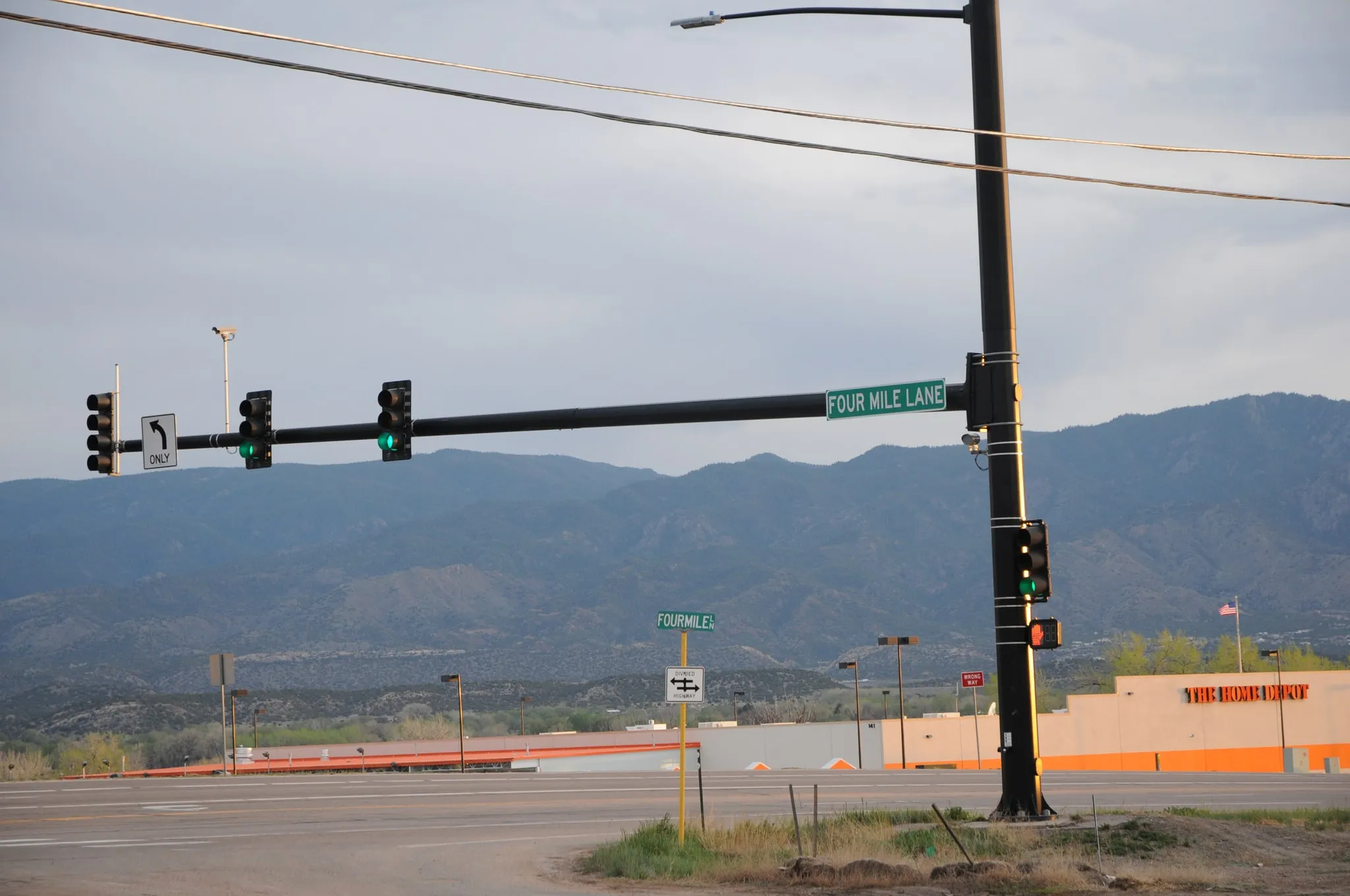 The traffic signal at the Four Mile Lane intersection on Highway 50, with the Home Depot store and the mountains visible beyond.
