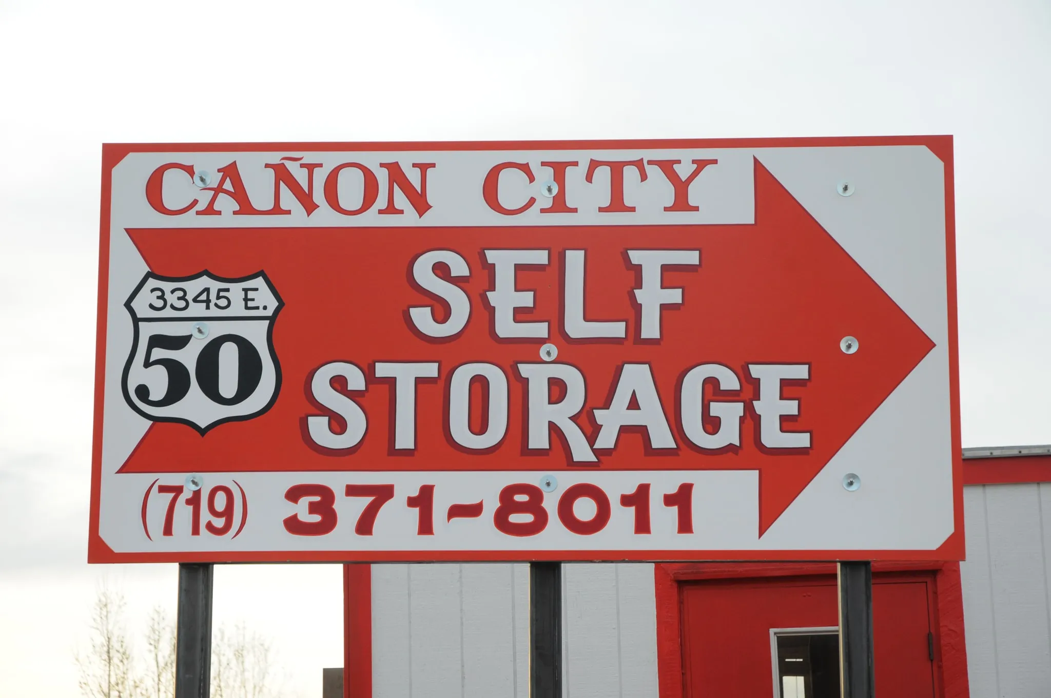 The red and white roadside sign reading Cañon City Self Storage, 3345 E. Highway 50, (719) 371-8011, with an arrow pointing toward the entrance.